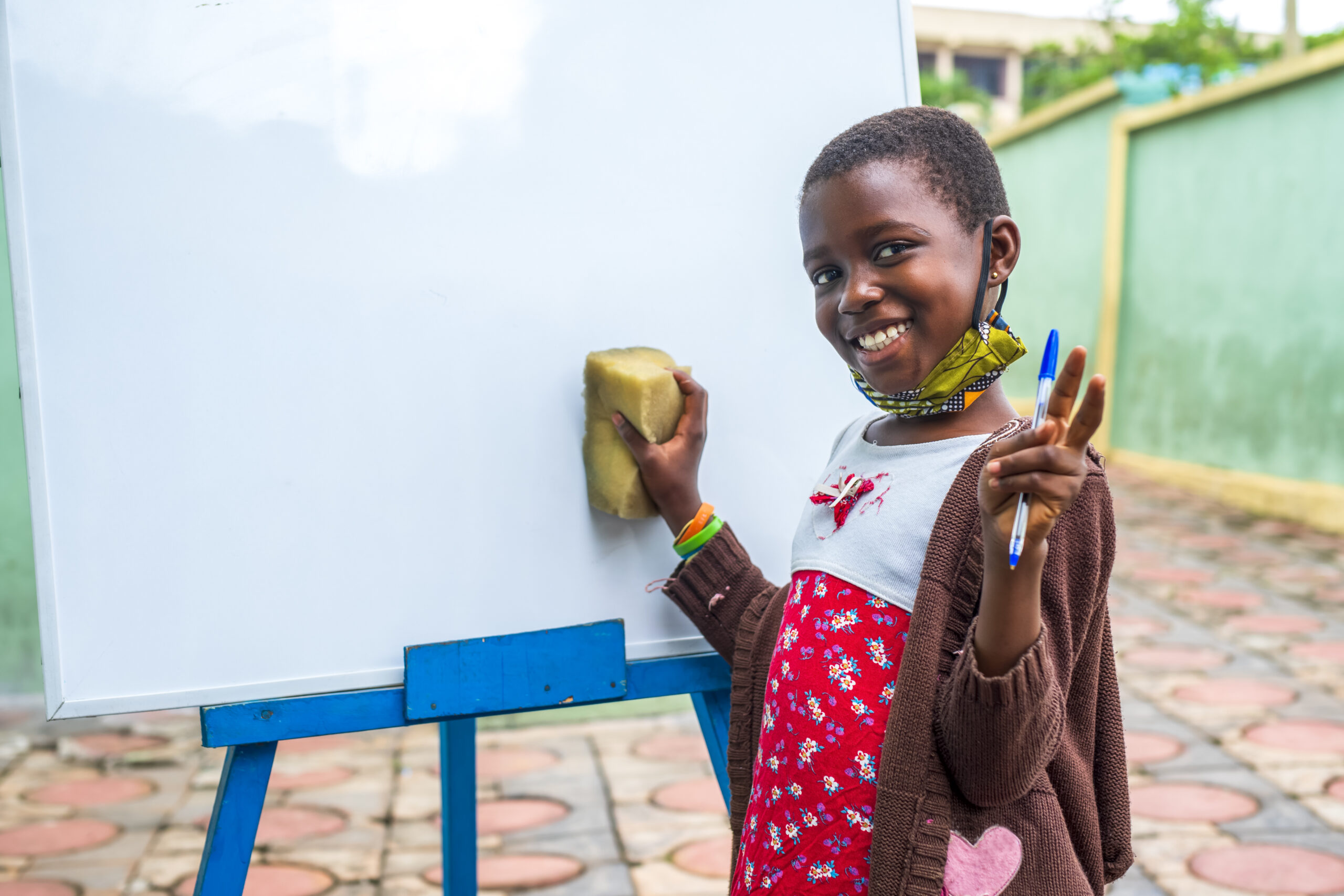 Closeup shot of a black male child erasing a whiteboard – education concept